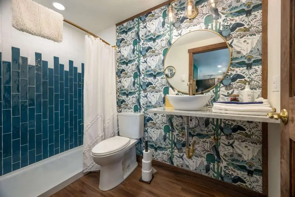 Bathroom with patterned wallpaper and round mirror