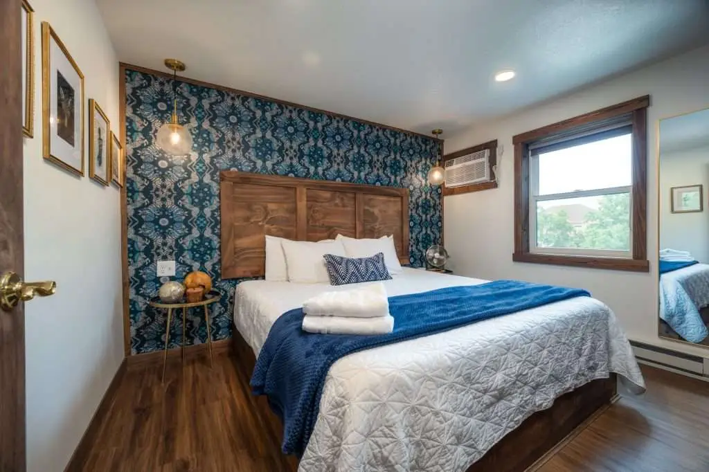 King bedroom with patterned wallpaper and wood headboard